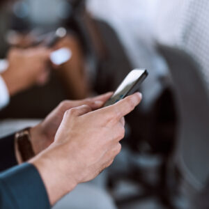 Cropped shot of a group of businesspeople using their mobile phones during a conference